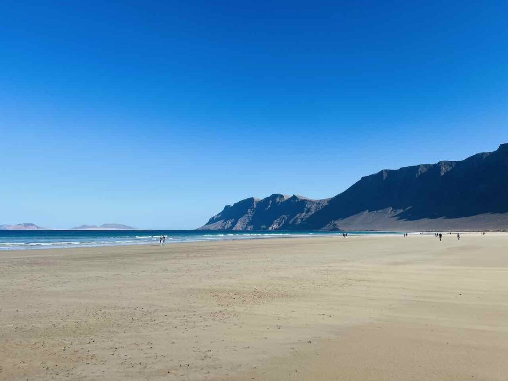 Weitläufiger Strand mit Bergen im Hintergrund auf Lanzarote