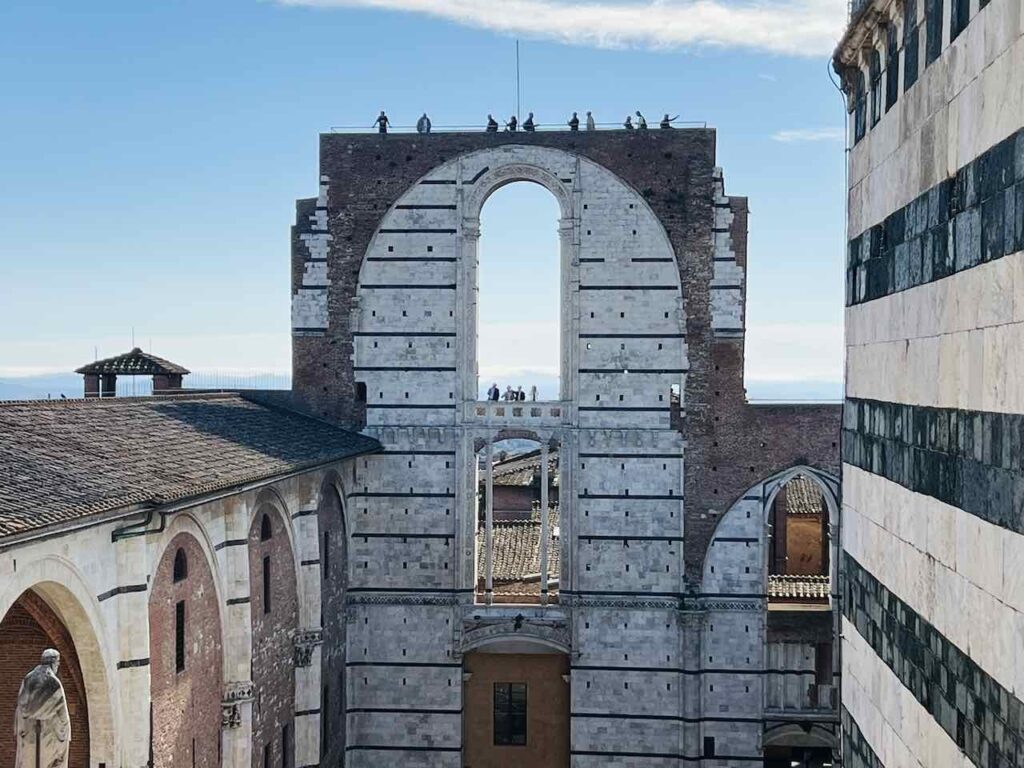 Menschen stehen oben auf dem Facciatone in Siena