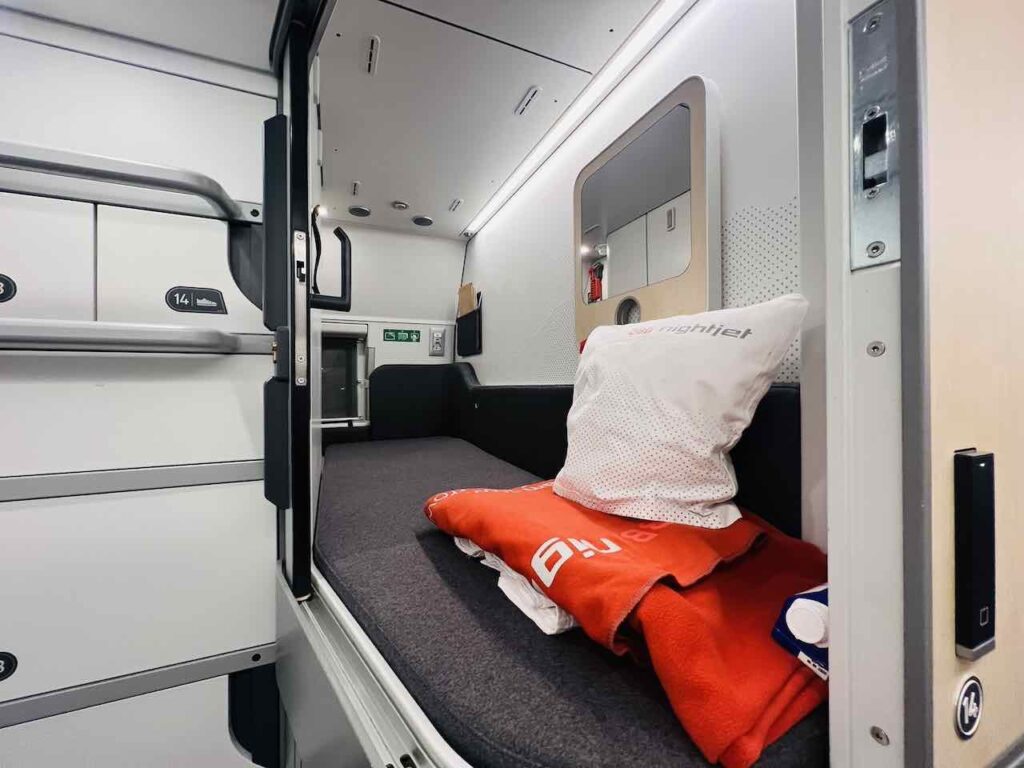 Blick in eine Mini Cabin, in der Kopfkissen, Decke und Laken bereit liegen.