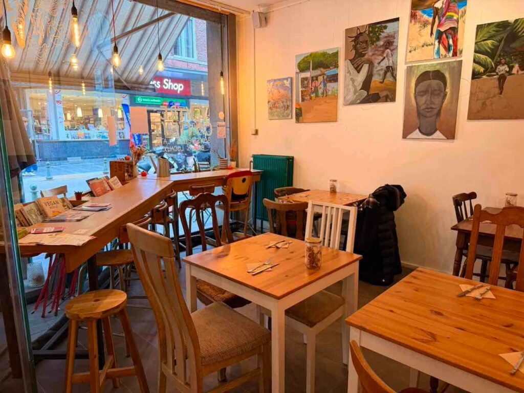 Gemütliches Restaurant in Lüttich mit Holztischen und Kunstwerken an der Wand.