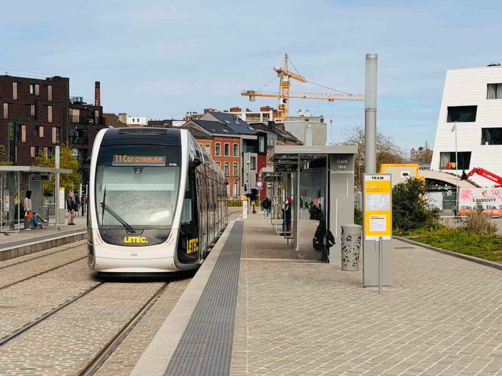 Staßenbahnhaltestelle am Bahnhof in Lüttich und auf den Gleisen steht eine Straßenbahn.
