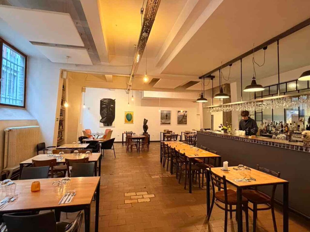 Modernes Restaurant in Lüttich mit Bar, Tischen und Gemälden an der Wand.